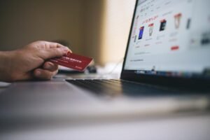 Person holding a credit card in front of a laptop showing an online store checkout page